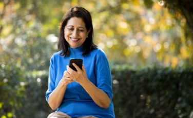Happy senior woman text messaging using mobile phone