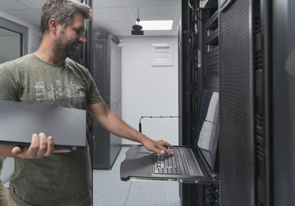 man working on laptop in server room