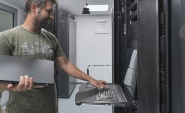 man working on laptop in server room